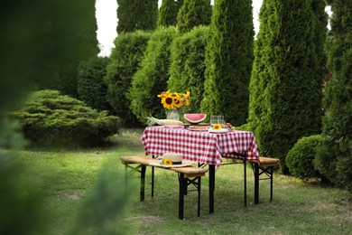 Photo of Fresh fruits, pie and vase with sunflowers on table in garden