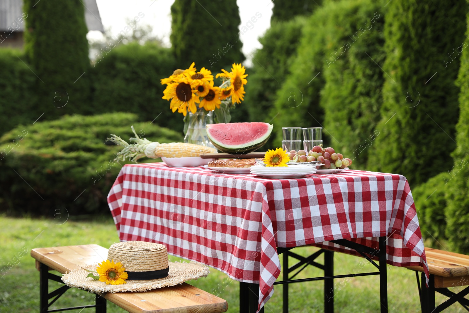 Photo of Fresh fruits, pie and vase with sunflowers on table in garden