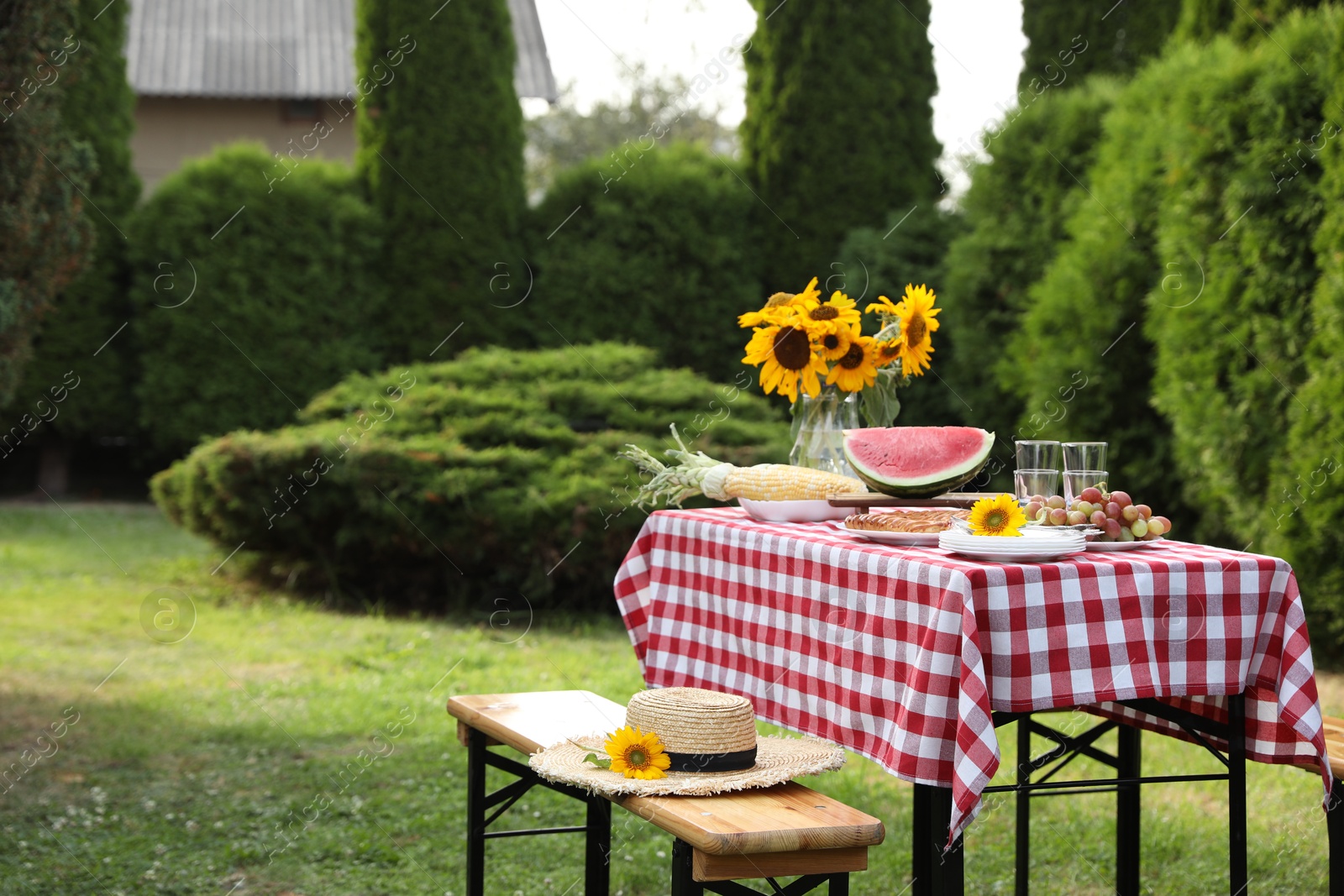 Photo of Fresh fruits, pie and vase with sunflowers on table in garden, space for text