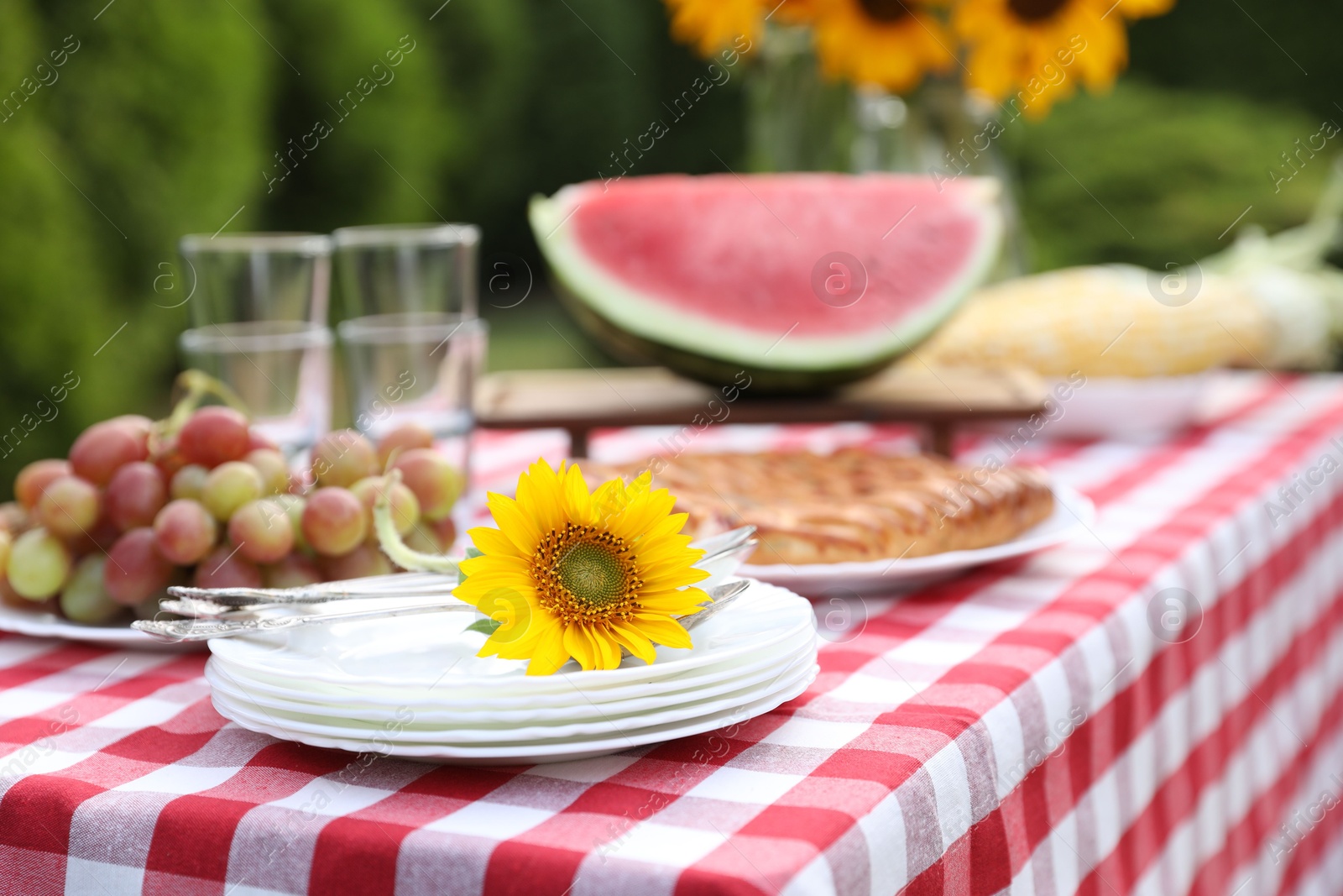 Photo of Fresh fruits, pie and vase with sunflowers on table in garden, closeup