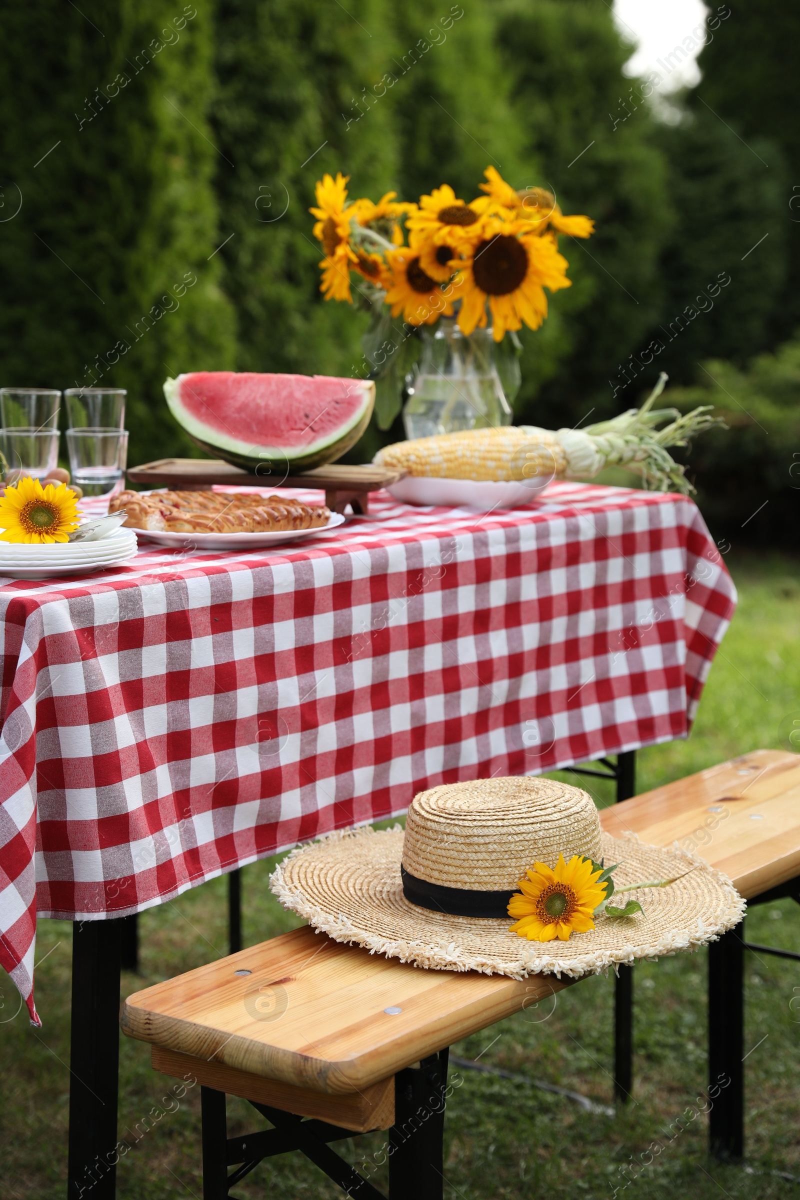 Photo of Fresh fruits, pie and vase with sunflowers on table in garden