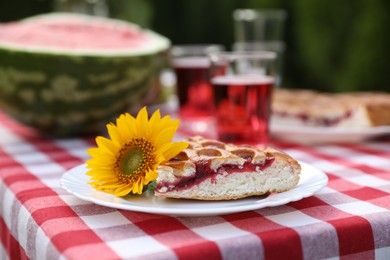 Photo of Plate with pie and sunflower on table in garden, closeup