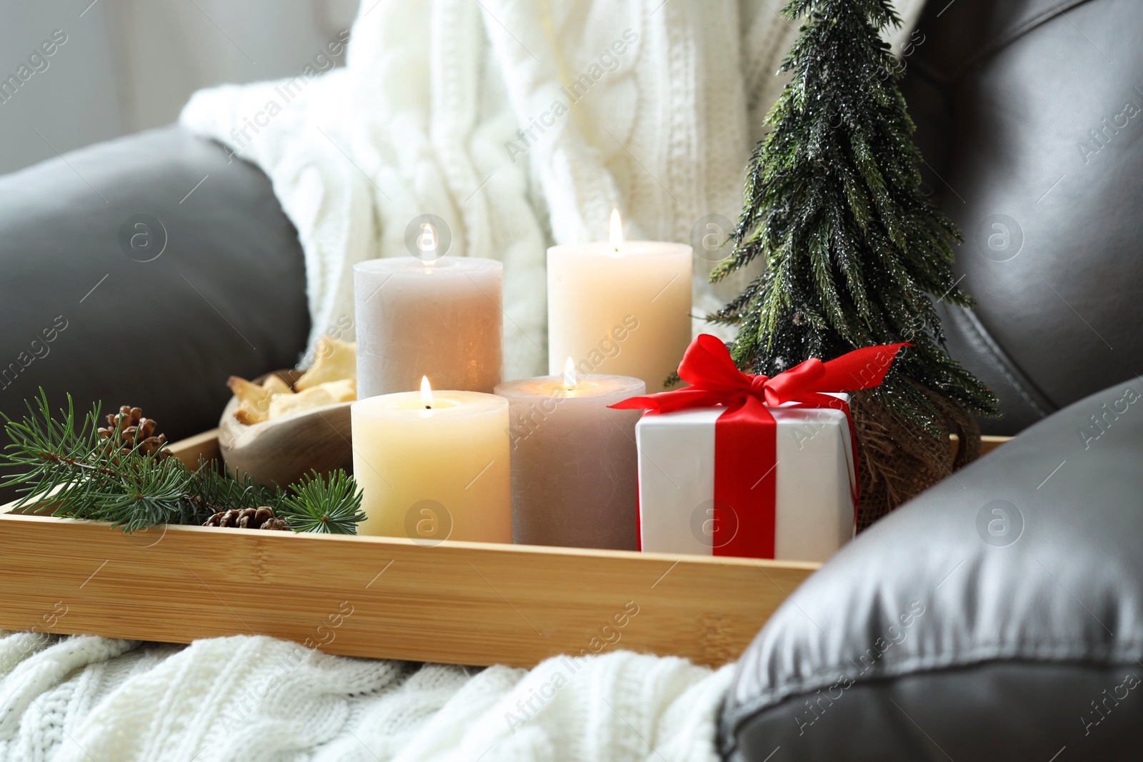 Photo of Tray with burning candles and Christmas decor on armchair