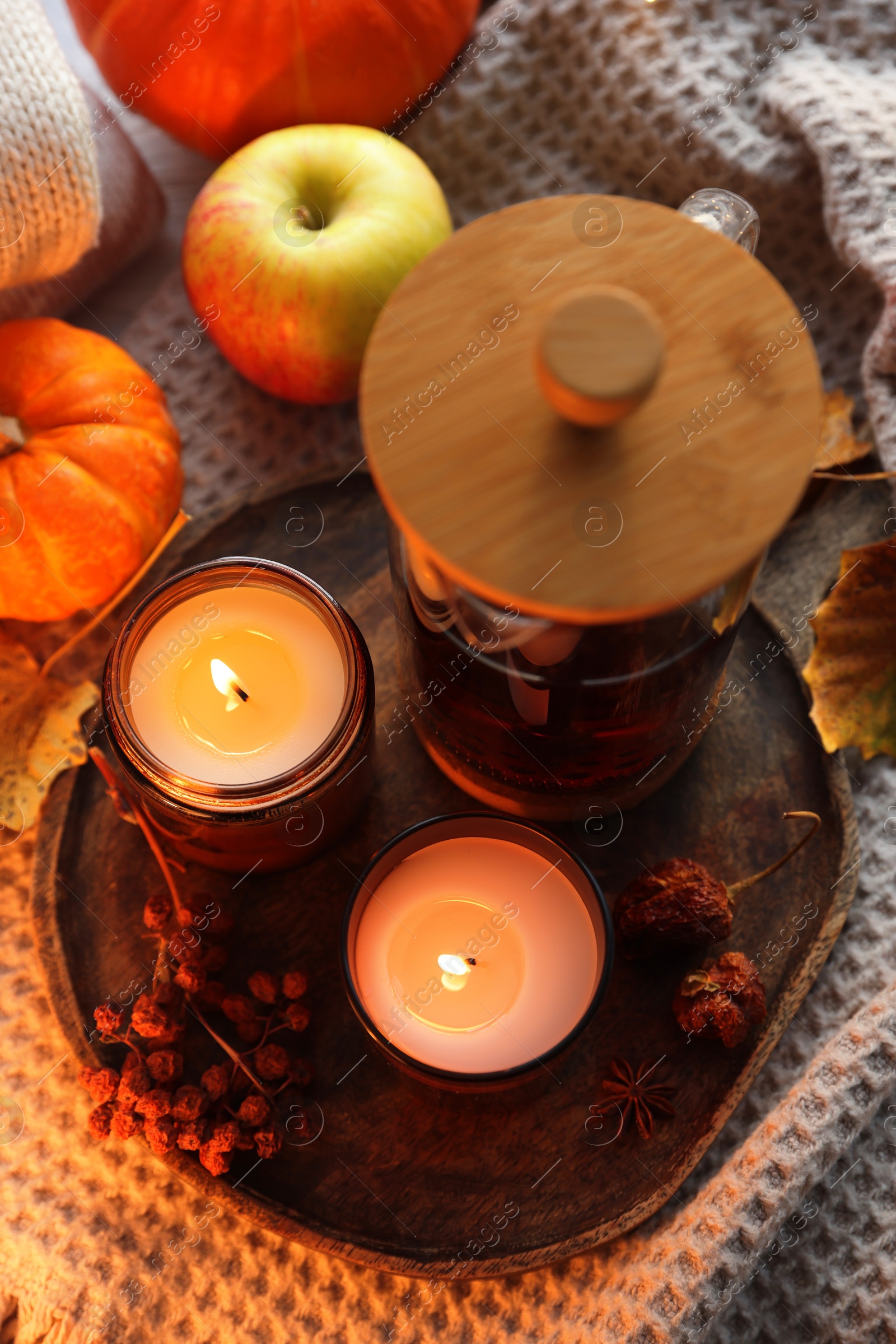 Photo of Burning candles, freshly brewed tea and autumn decor on fabric, above view