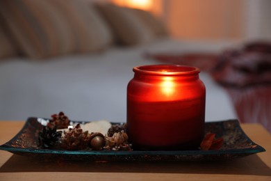 Photo of Burning candle and dry flowers on wooden table indoors, closeup. Autumn atmosphere