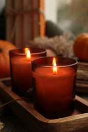 Autumn atmosphere. Burning candles on table, closeup