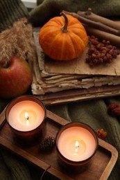 Photo of Burning candles, old books and autumn decor on green sweater, above view