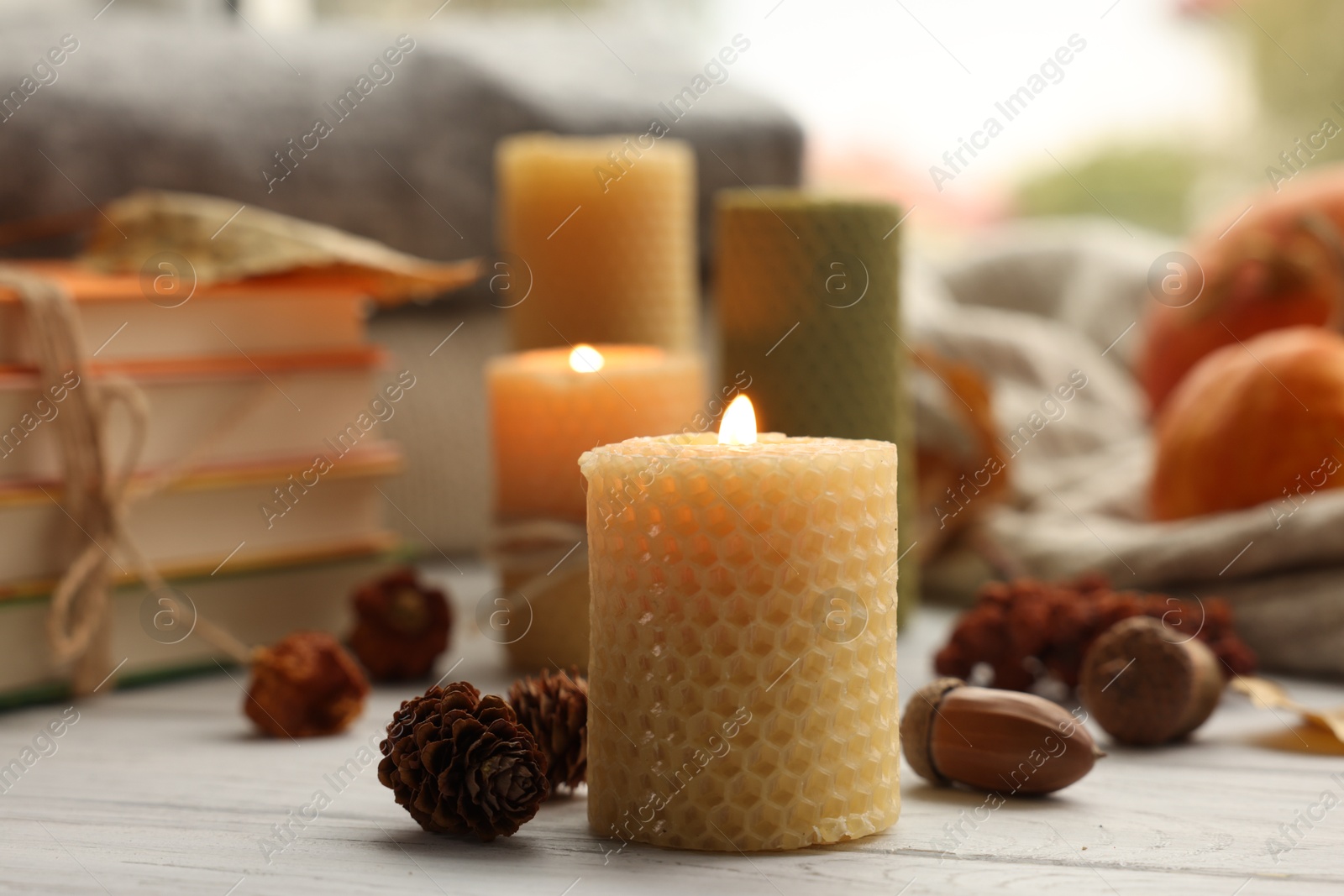 Photo of Burning candles, books and autumn decor on grey wooden table