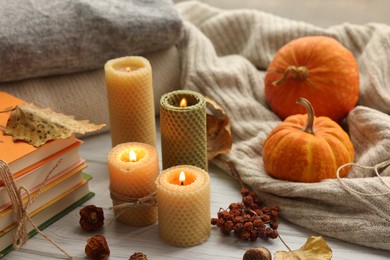 Photo of Burning candles, books, sweaters and autumn decor on grey wooden table