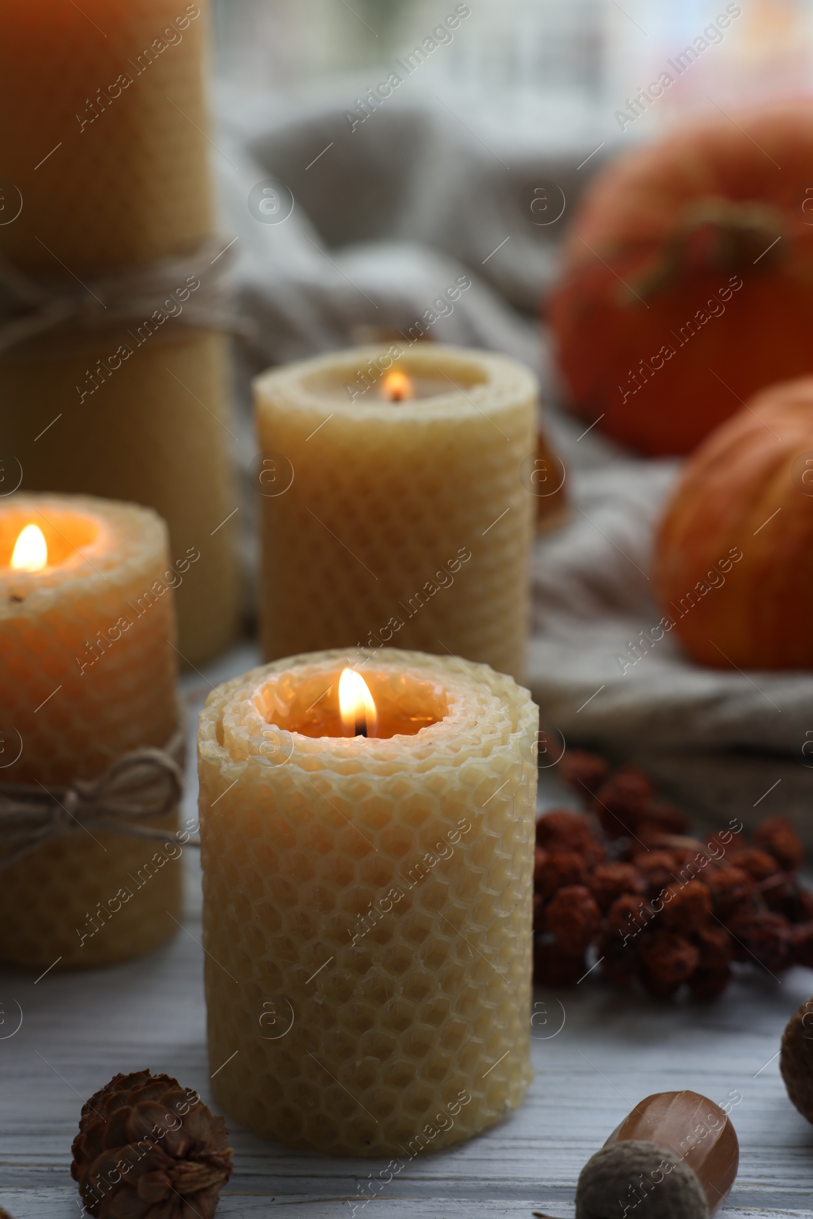 Photo of Burning candles and autumn decor on grey wooden table, closeup