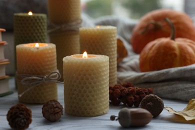 Photo of Burning candles and autumn decor on grey wooden table