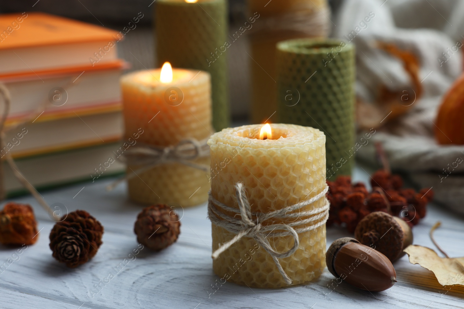 Photo of Burning candles and autumn decor on grey wooden table, closeup