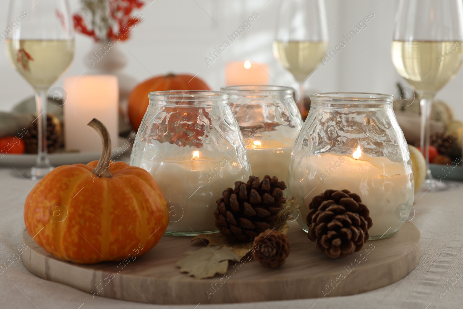 Photo of Burning candles and autumn decor on table indoors, closeup