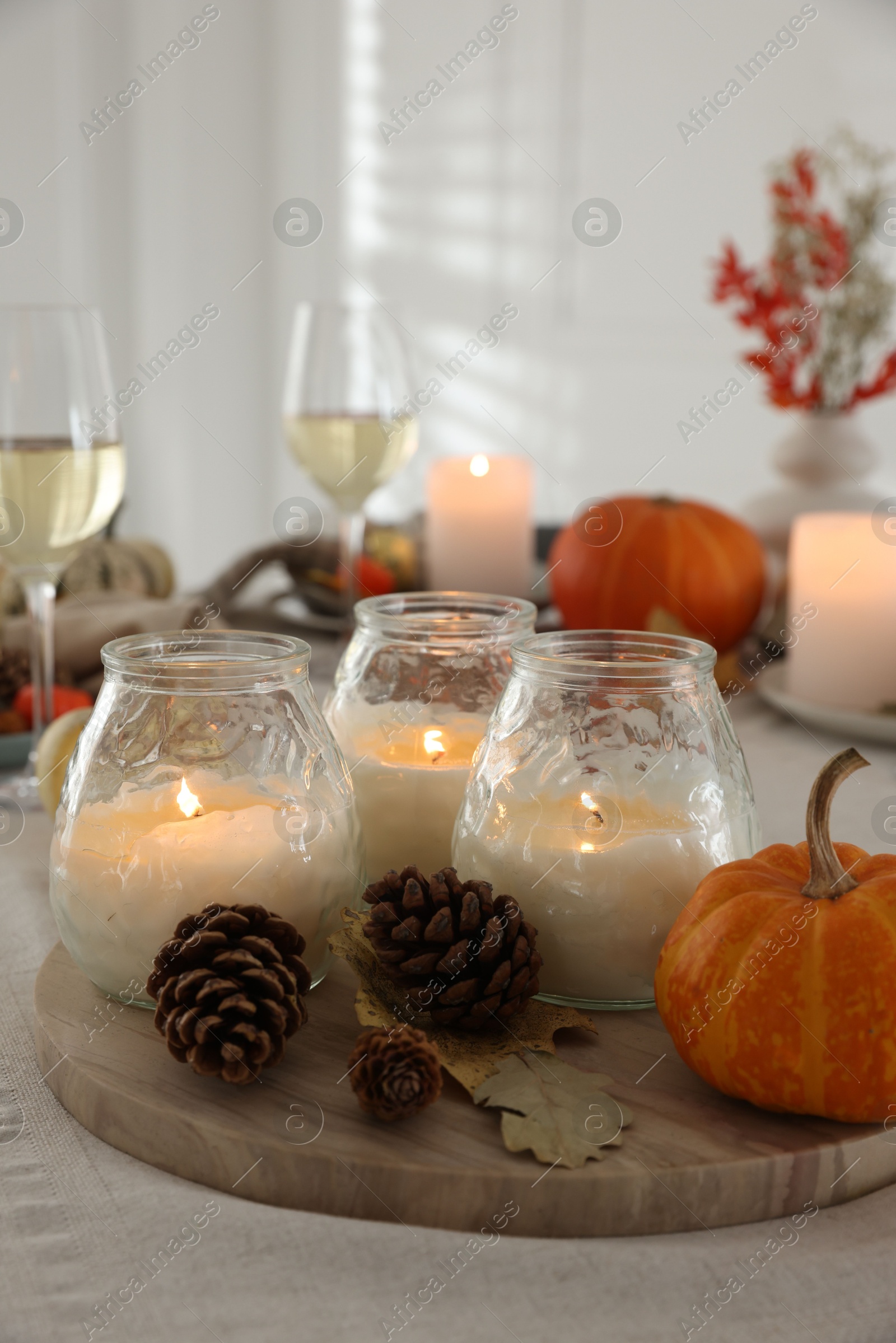 Photo of Burning candles and autumn decor on table indoors