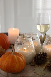 Photo of Burning candles and autumn decor on table, closeup