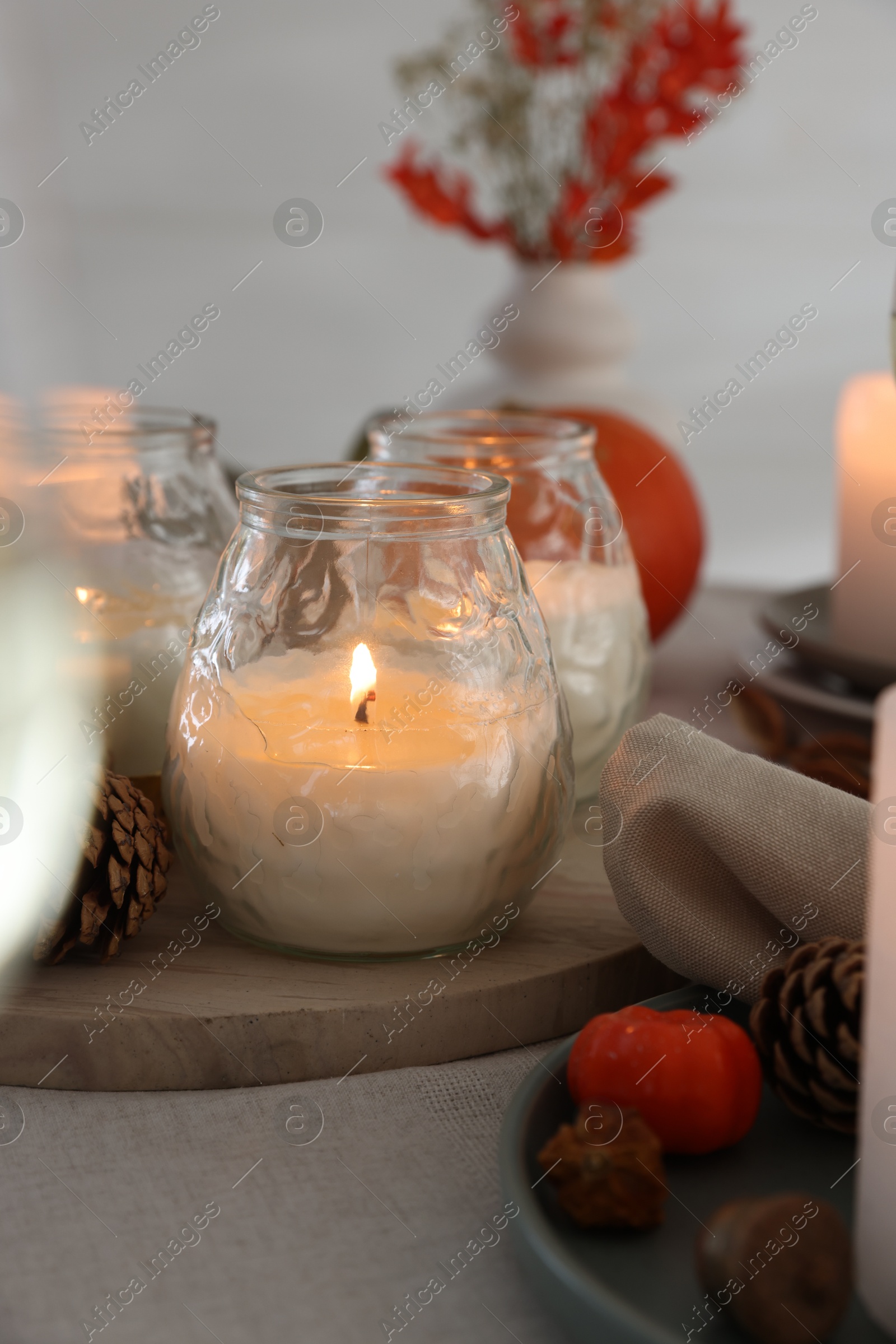 Photo of Burning candles and autumn decor on table, closeup