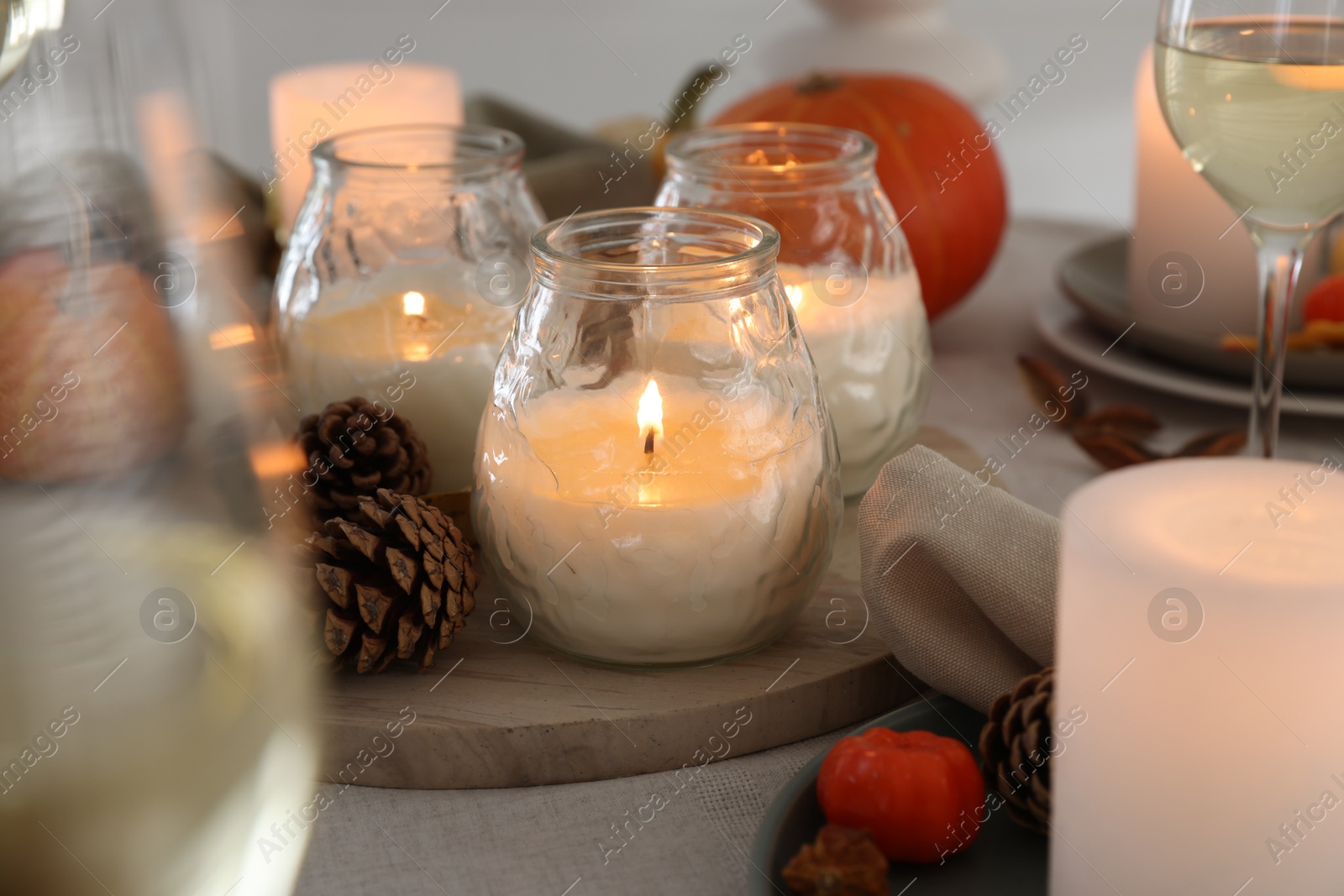 Photo of Burning candles and autumn decor on table, closeup