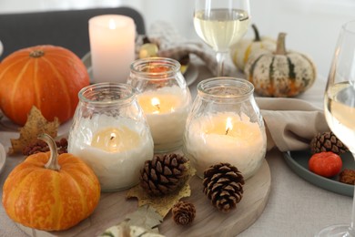 Photo of Burning candles and autumn decor on table, closeup