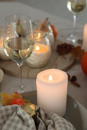 Photo of Burning candles, glass of wine and autumn decor on table, closeup