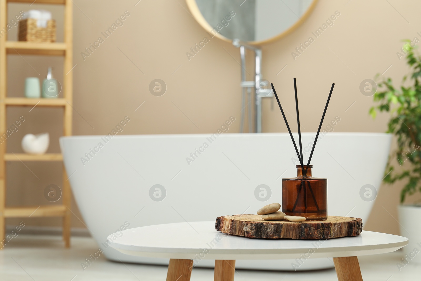 Photo of Reed diffuser and stones on table in bathroom. Space for text