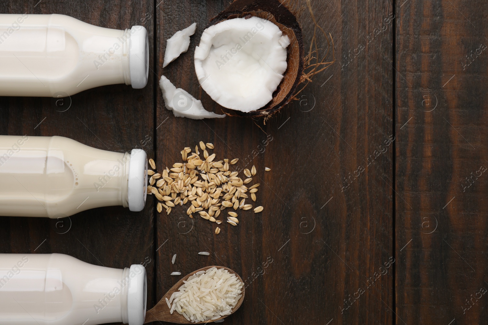 Photo of Different types of vegan milk in bottles and ingredients on wooden table, flat lay. Space for text