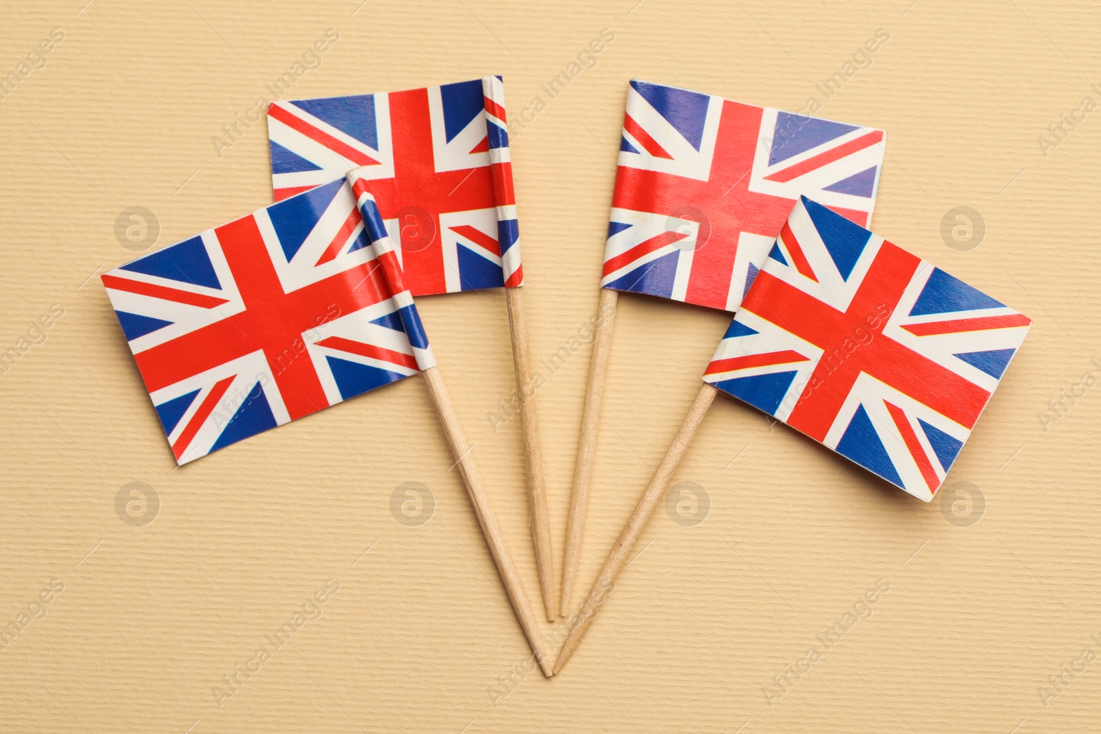 Photo of Small paper flags of United Kingdom on beige background, top view