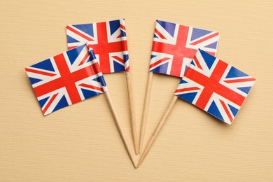 Small paper flags of United Kingdom on beige background, top view