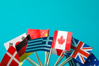 Photo of Small paper flags of different countries on light blue background