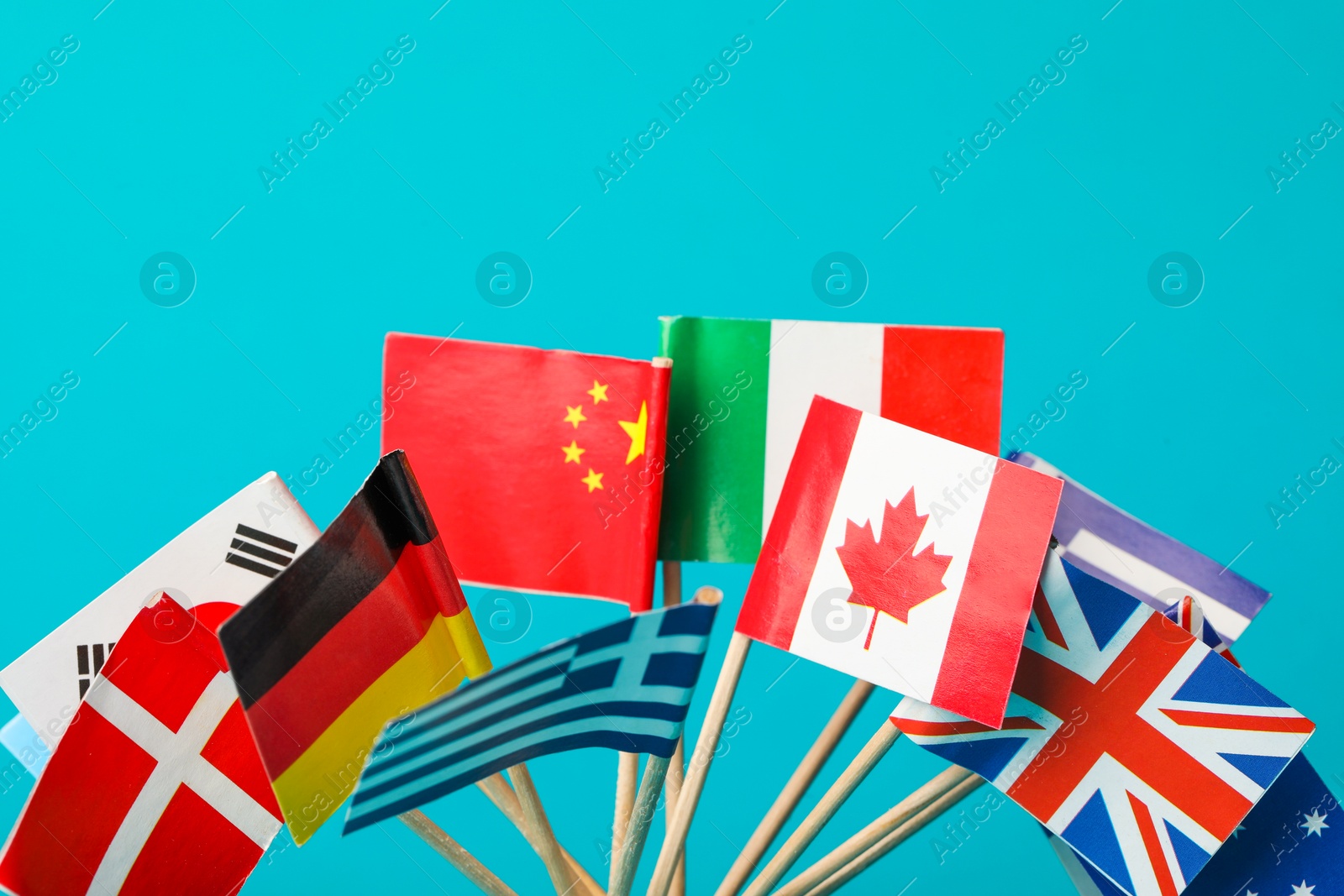 Photo of Small paper flags of different countries on light blue background