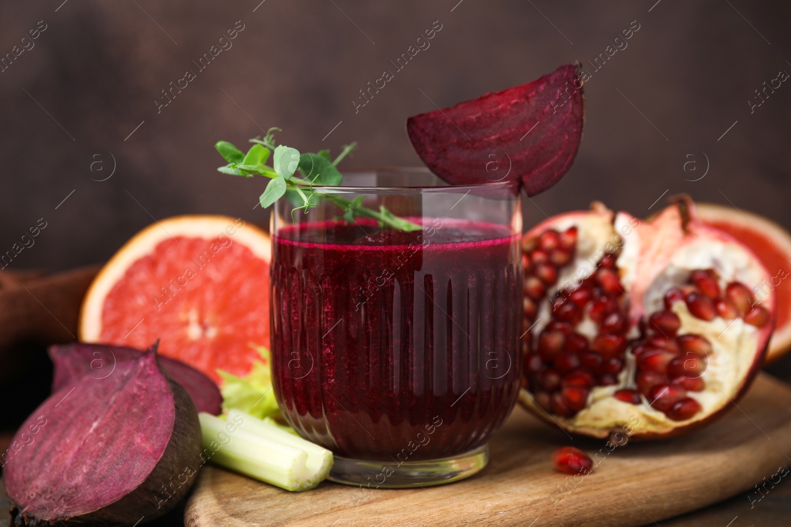 Photo of Tasty beetroot smoothie with microgreens in glass, fresh vegetables and fruits on table, closeup. Vegan drink