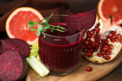 Photo of Tasty beetroot smoothie with microgreens in glass, fresh vegetables and fruits on table, closeup. Vegan drink