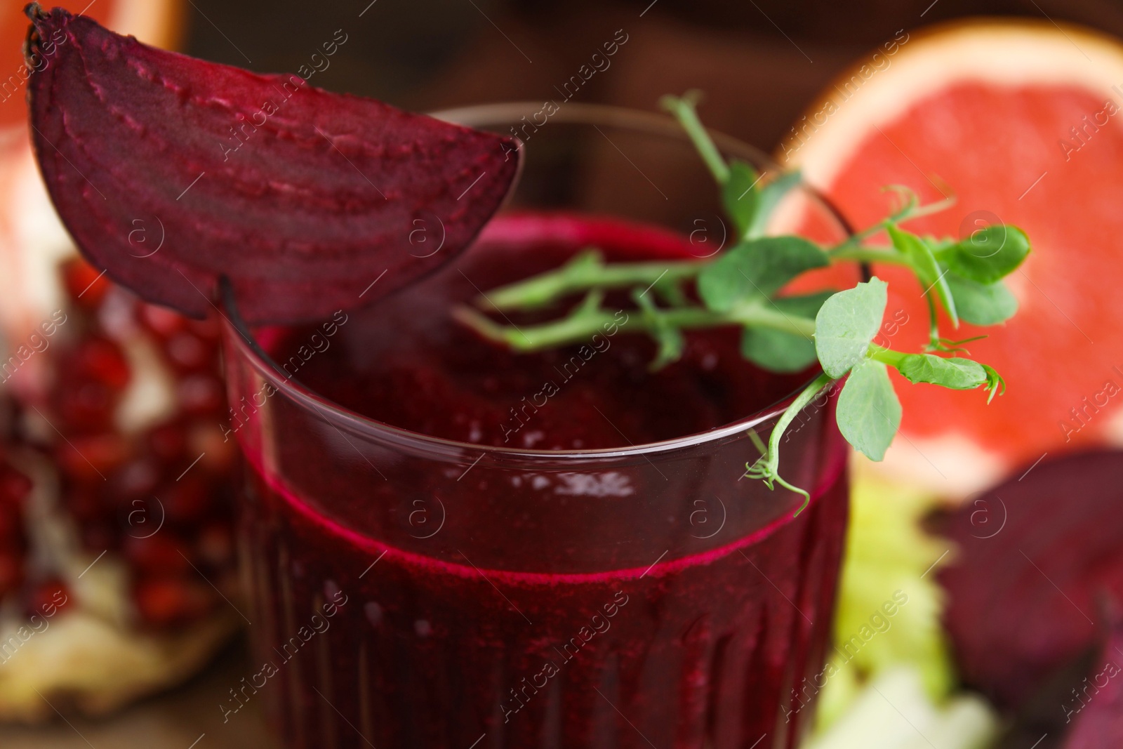 Photo of Tasty beetroot smoothie with microgreens in glass on table, closeup. Vegan drink