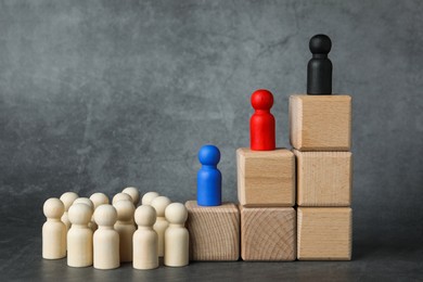 Photo of Different figures on wooden ladder against grey background