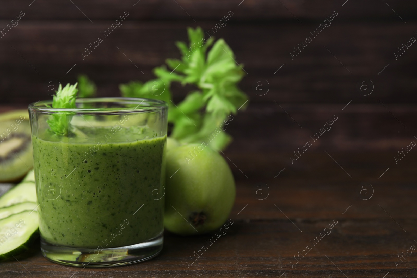 Photo of Tasty green smoothie in glass and products on wooden table, closeup. Space for text