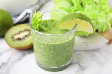 Photo of Tasty green smoothie in glass with lime and products on white marble table, closeup