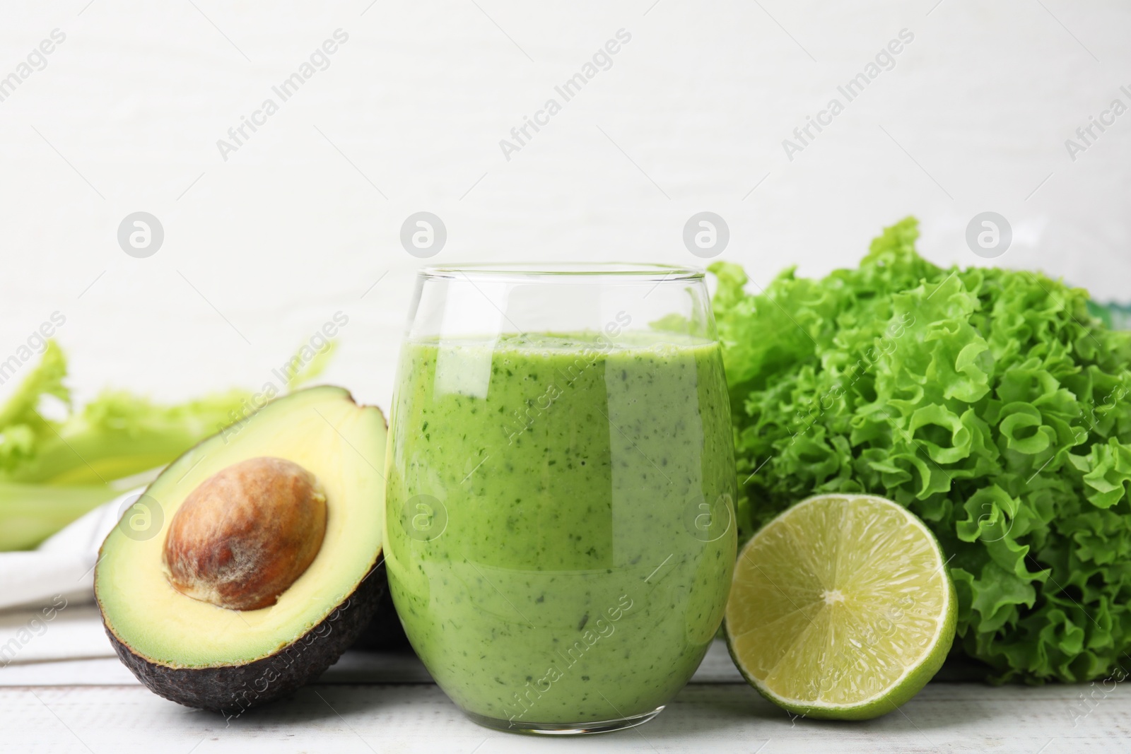 Photo of Tasty green smoothie in glass and products on wooden rustic table, closeup