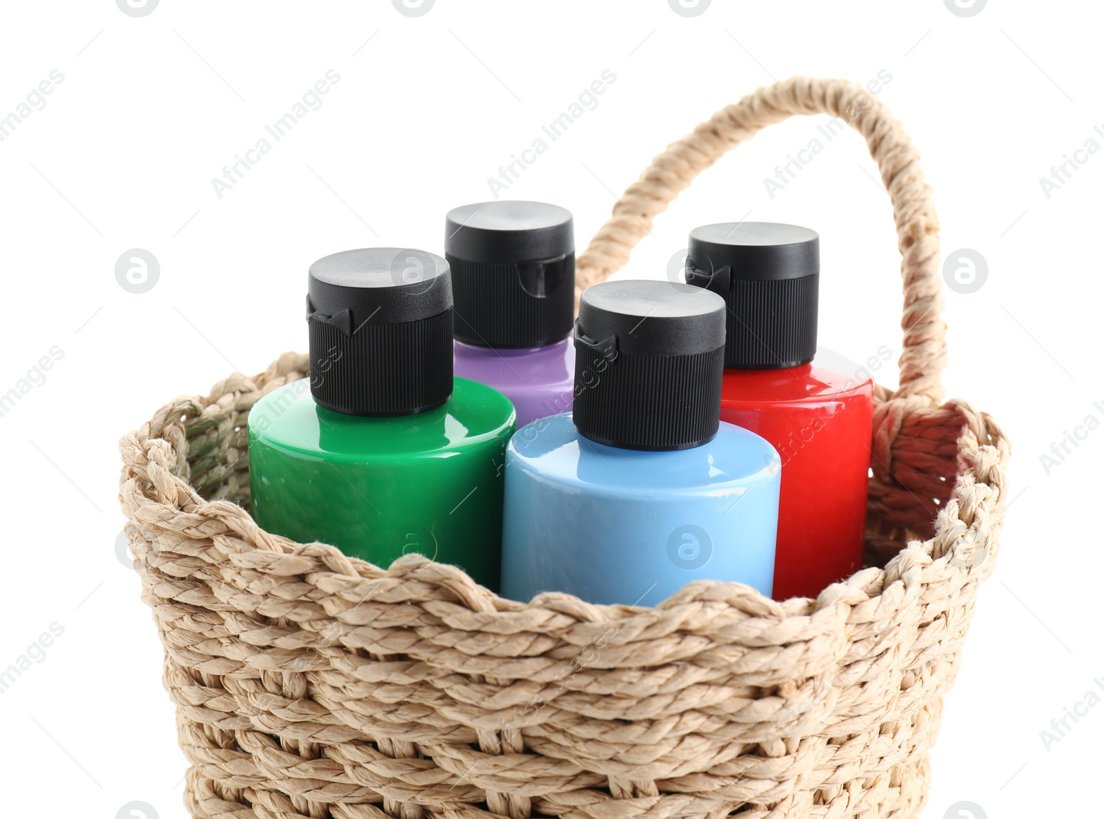 Photo of Bottled acrylic paints of different colors in wicker basket isolated on white