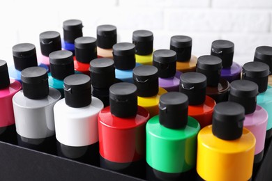 Acrylic paints of different colors in bottles against white background, closeup