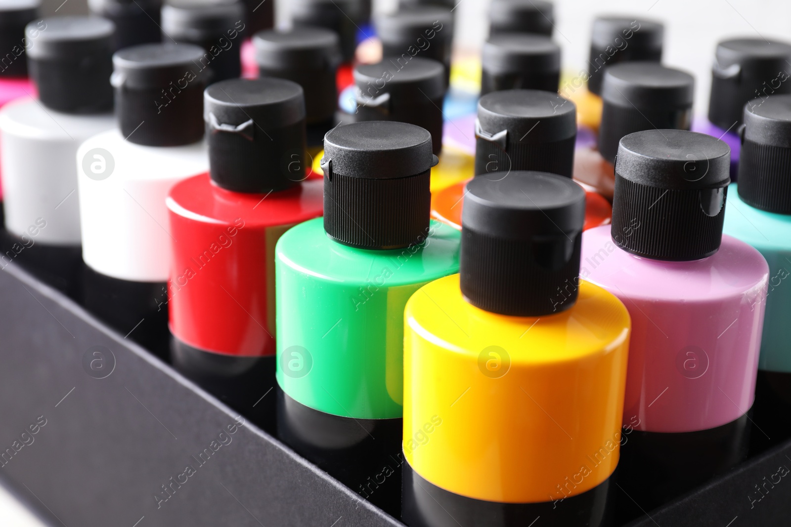 Photo of Acrylic paints of different colors in bottles on table closeup