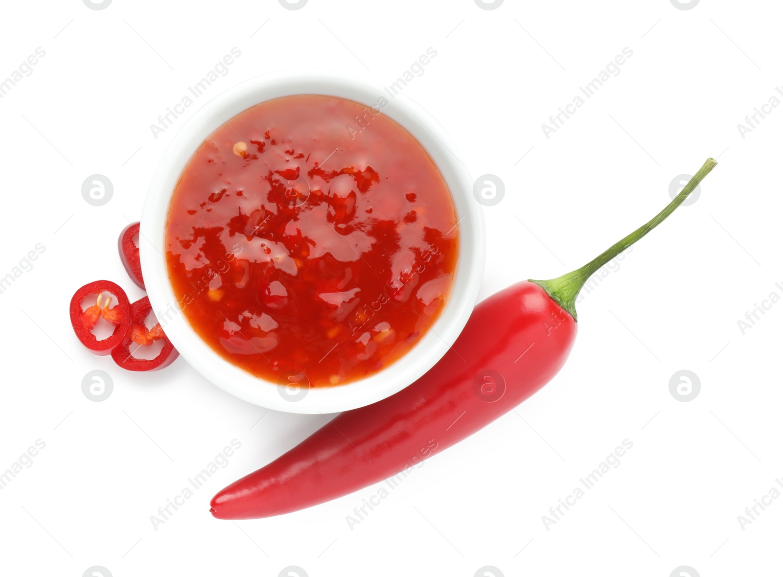 Photo of Hot chili sauce in bowl and pepper isolated on white, top view