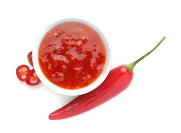 Photo of Hot chili sauce in bowl and pepper isolated on white, top view