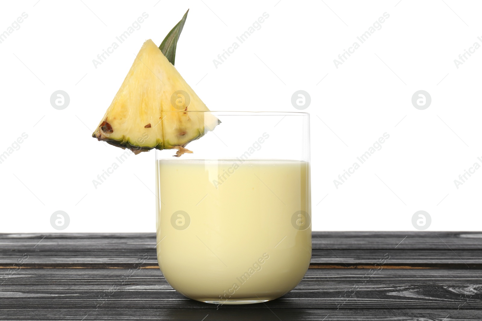 Photo of Tasty pineapple smoothie in glass and slice of fruit on wooden table against white background