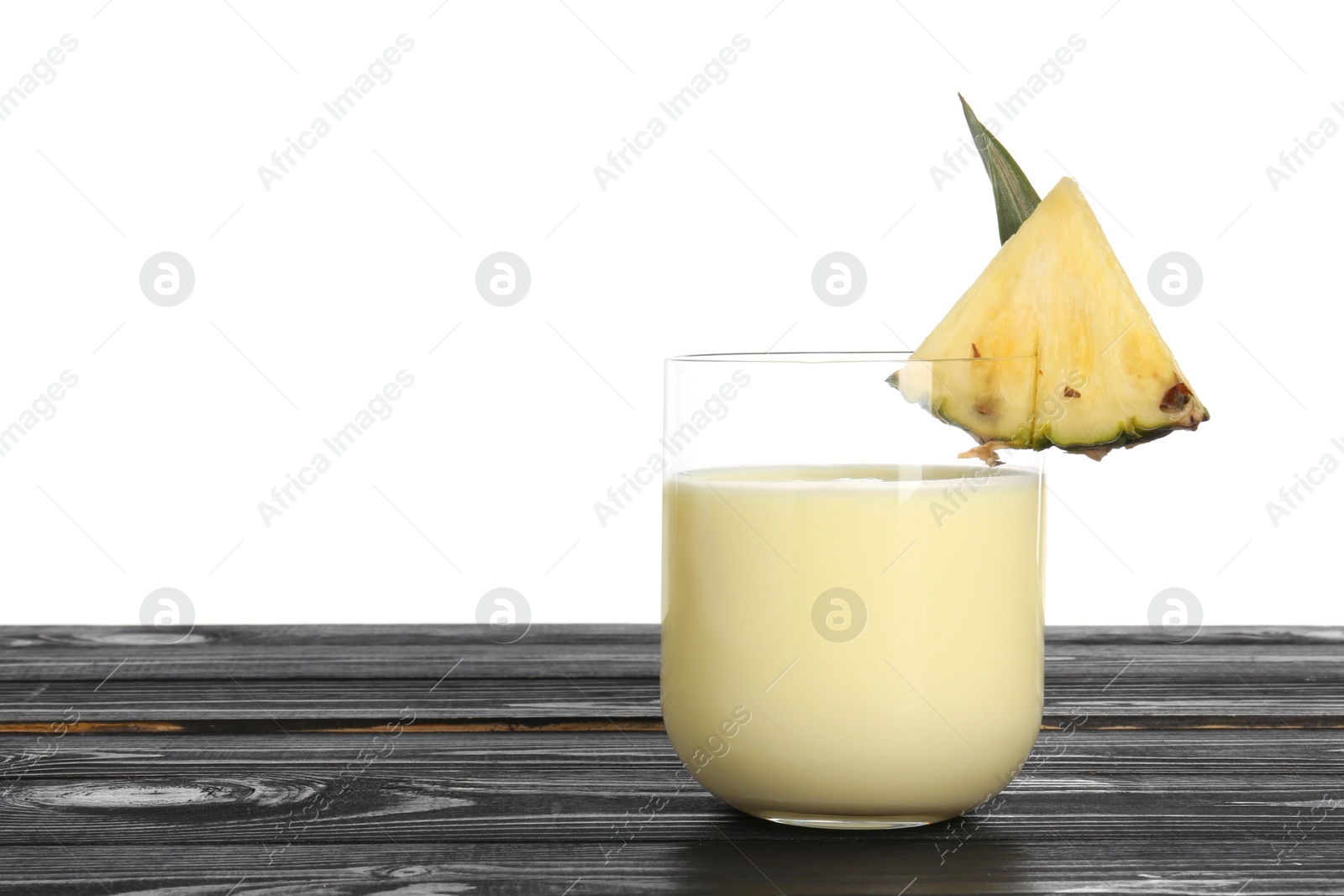 Photo of Tasty pineapple smoothie in glass and slice of fruit on wooden table against white background. Space for text