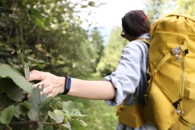 Photo of Young hiker with backpack walking in forest, selective focus