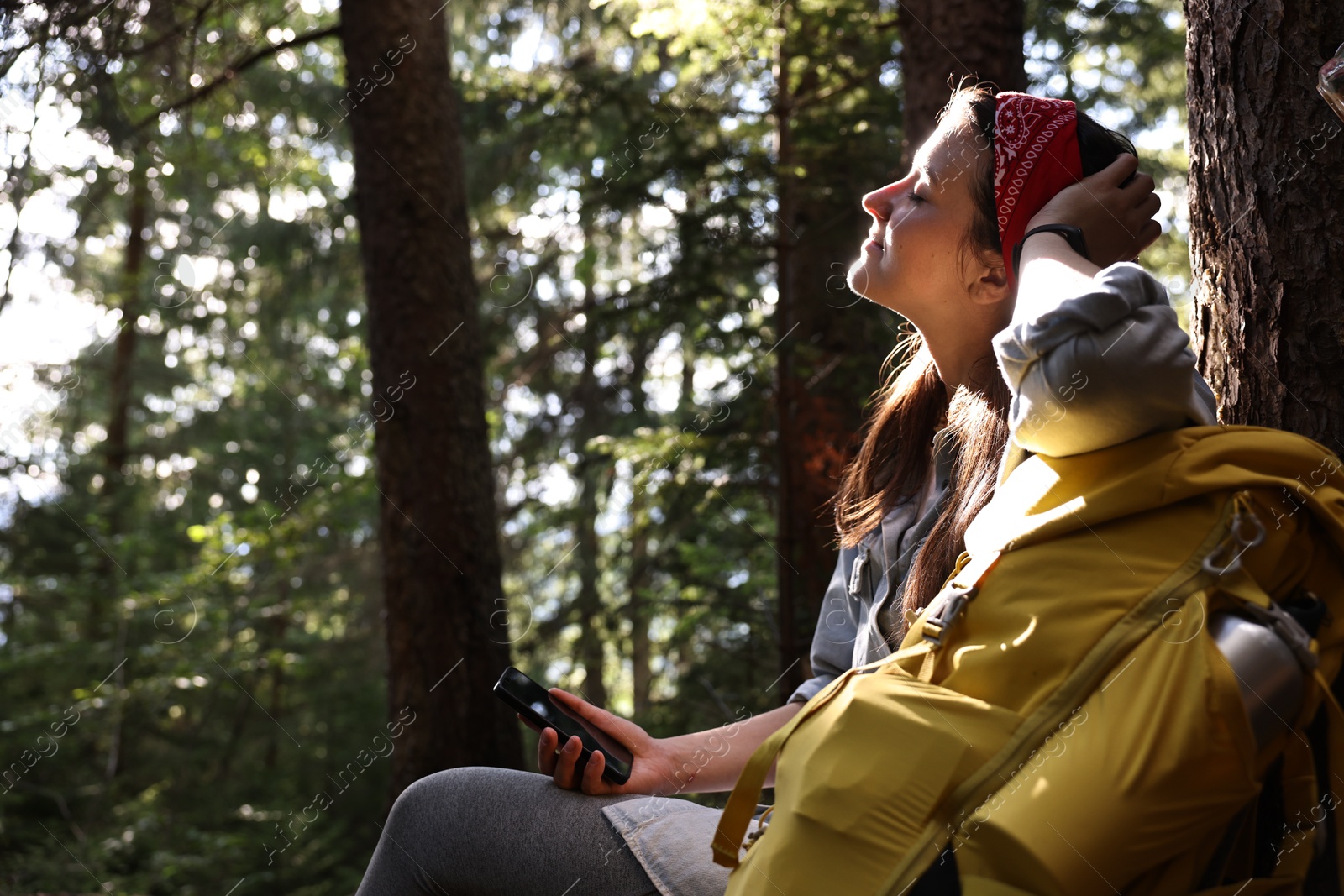 Photo of Young hiker with smartphone in forest, low angle view