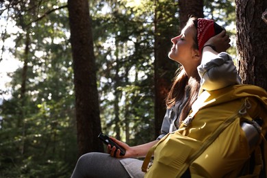 Young hiker with smartphone in forest, low angle view