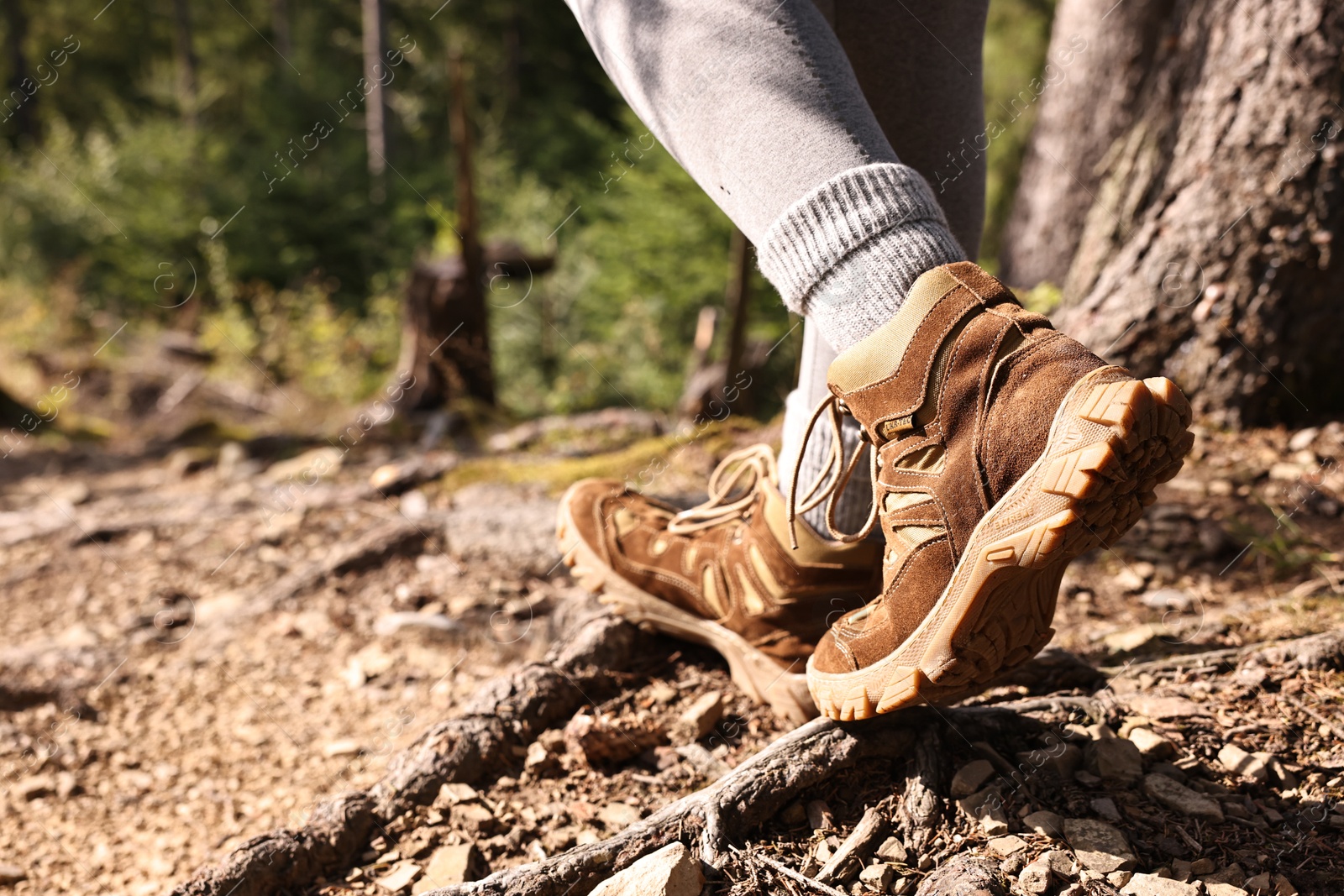 Photo of Young hiker in trekking shoes walking outdoors, closeup