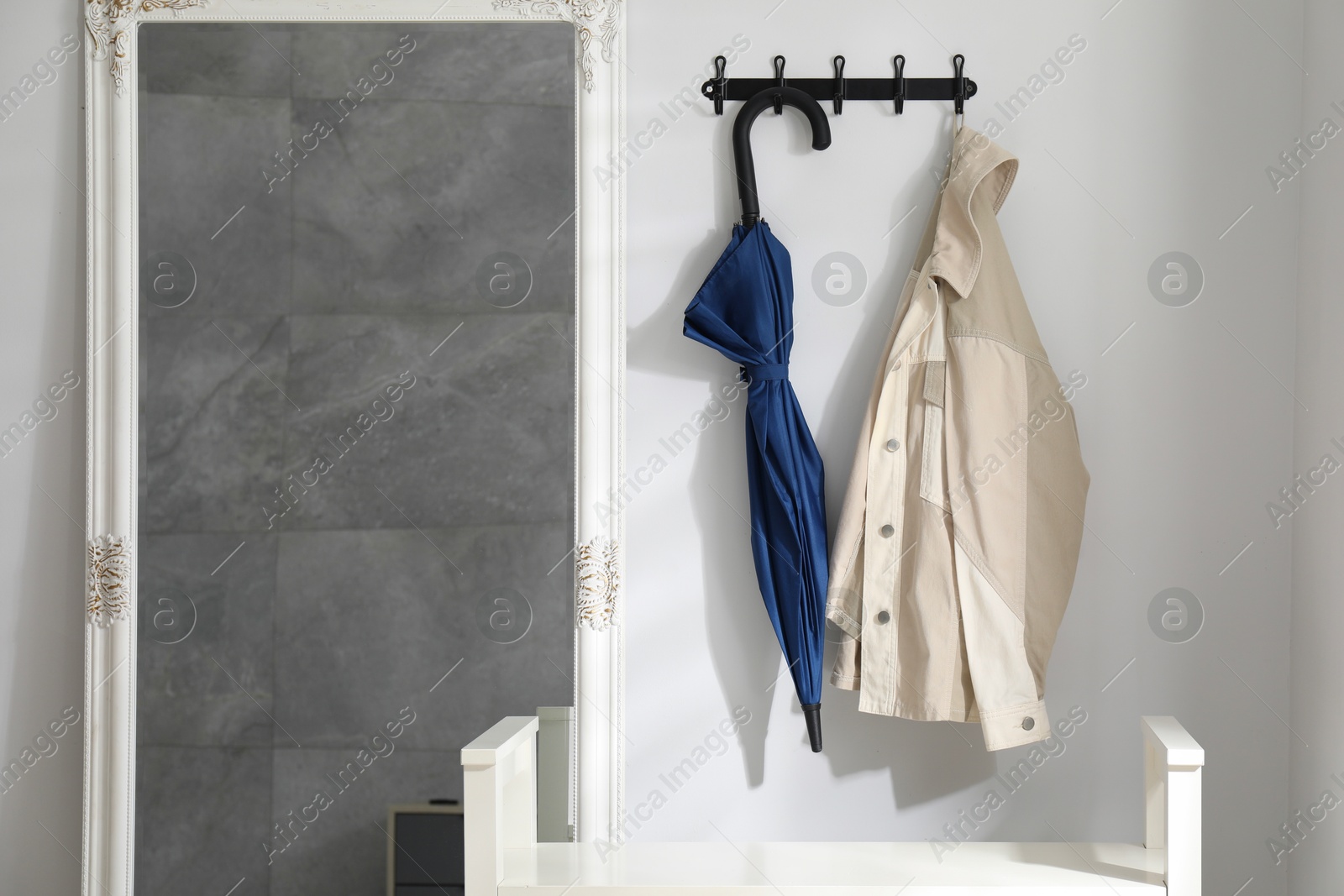 Photo of Blue umbrella and jacket on hanger near mirror indoors