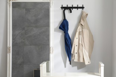 Photo of Blue umbrella and jacket on hanger near mirror indoors