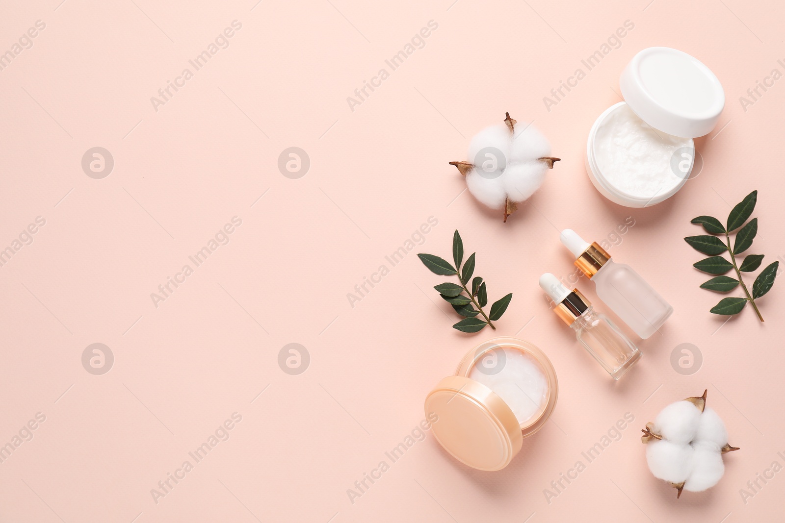 Photo of Different cosmetic products, leaves and cotton flowers on beige background, flat lay. Space for text